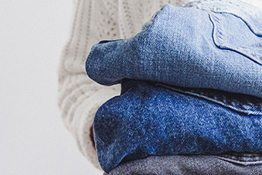Person holding a folded stack of blue denim jeans.