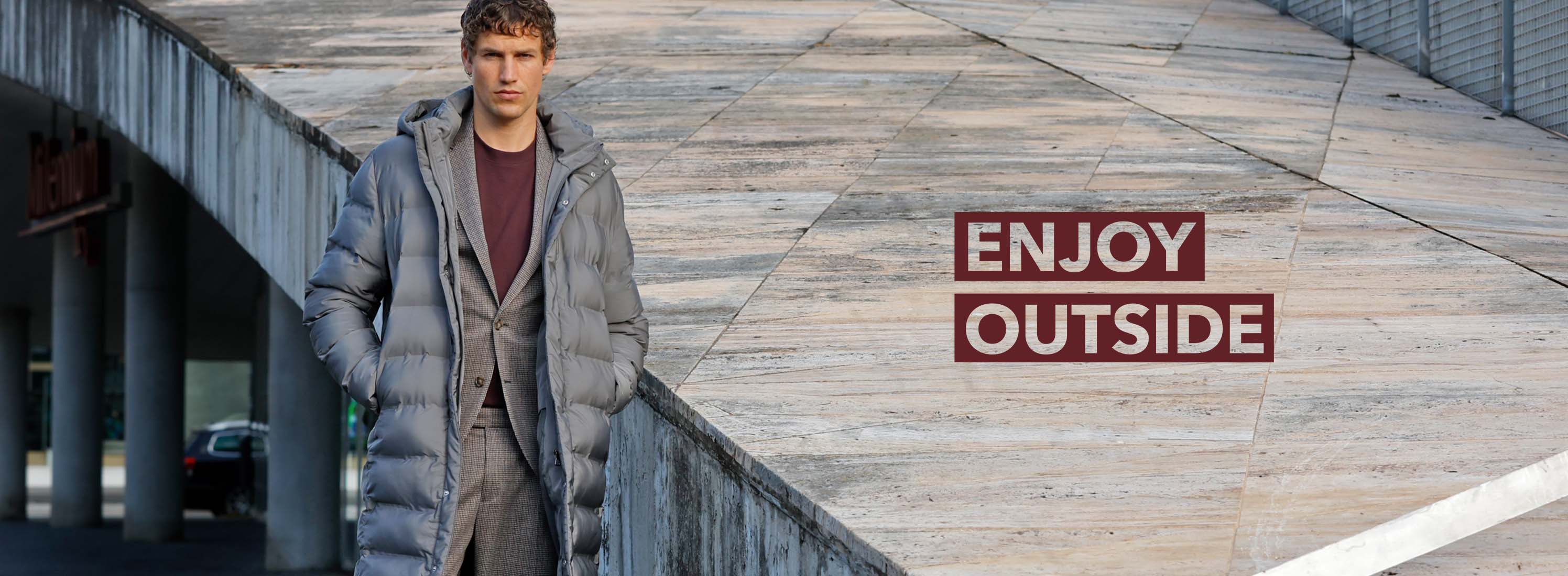 Mann trägt grauen Steppmantel und einen braun karierten Anzug